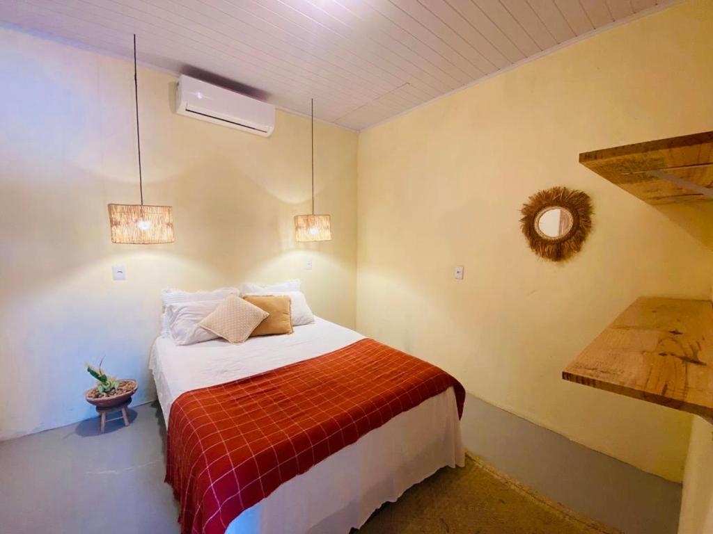 een slaapkamer met een bed met een rode deken bij Casas na vila de Caraíva in Caraíva