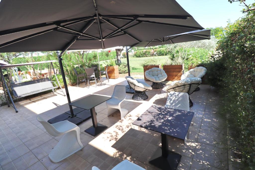 een patio met een tafel en stoelen en een parasol bij Chambres d'hôtes avec Jacuzzi et Piscine au Mas de Cadoule in Saint-Just
