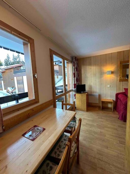 - un salon avec une table en bois et une grande fenêtre dans l'établissement Appartement Courchevel les brigues, à Courchevel
