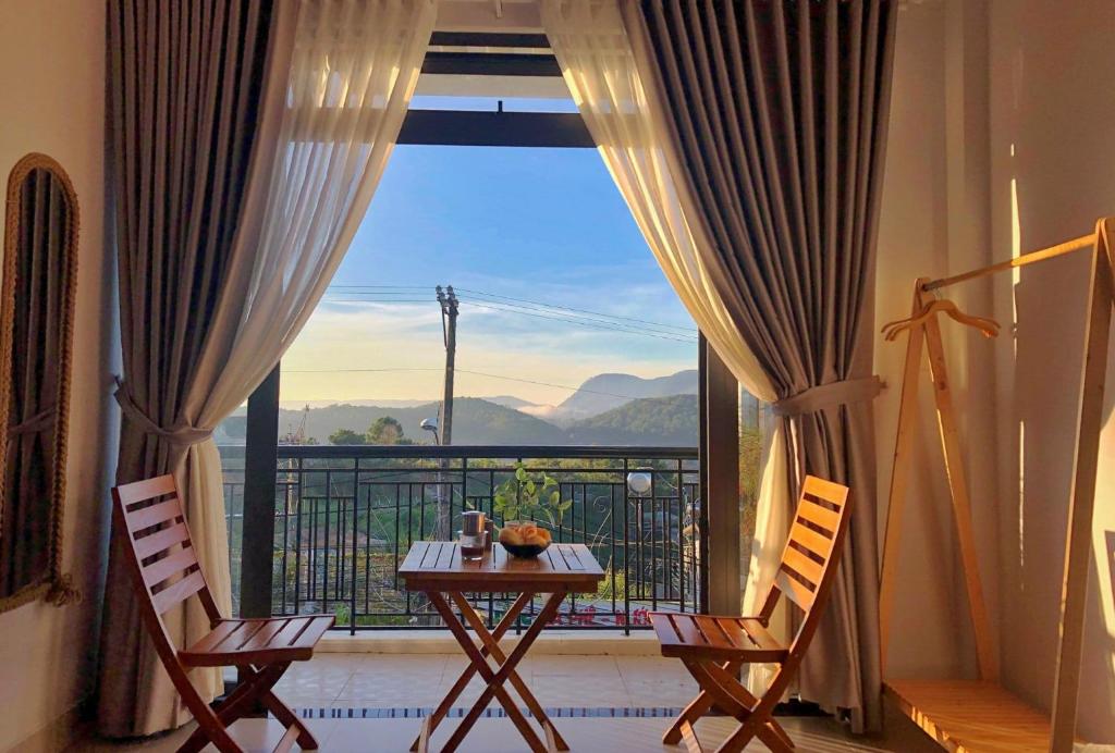 a room with a table and chairs and a large window at LaMay Homestay in Da Lat