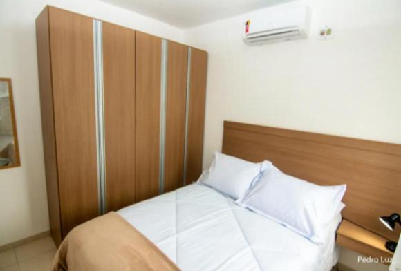 Apart Sol Nascente في إيتاتيايا: غرفة نوم مع سرير مع اللوح الأمامي الخشبي