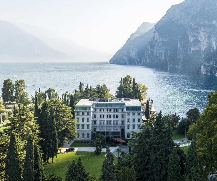 a large white building on the side of a lake at Lido Palace - The Leading Hotels of the World in Riva del Garda