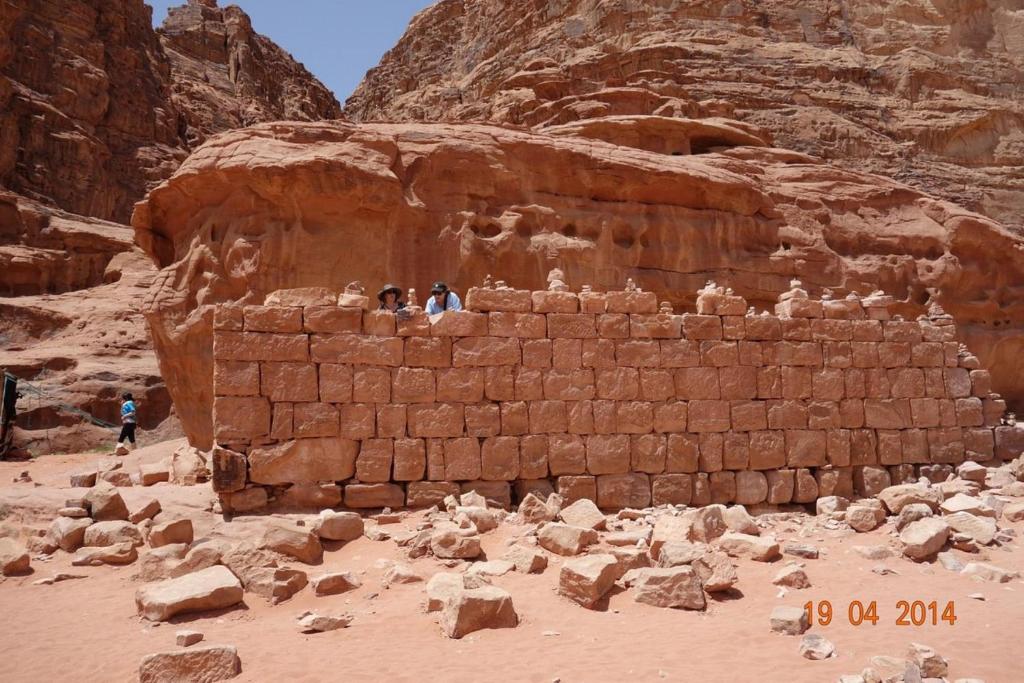 un grupo de personas sentadas en una pared de ladrillo en el desierto en Calm Camp en Wadi Rum