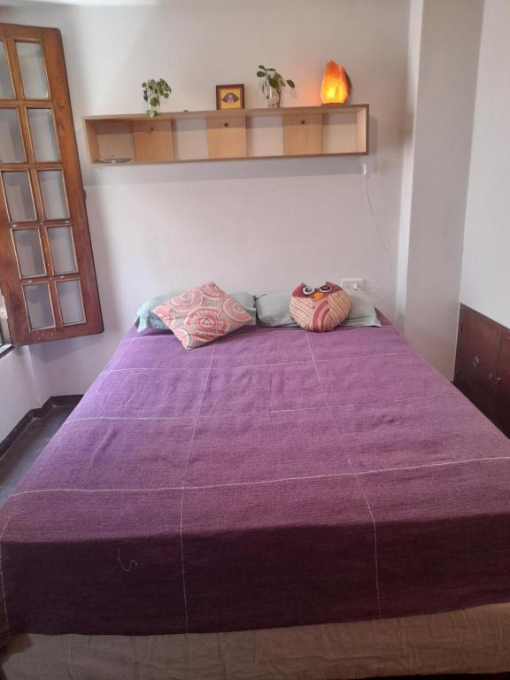 1 dormitorio con 1 cama púrpura y 2 almohadas en Casabunda Multiespacio - Habitación privada en Salta