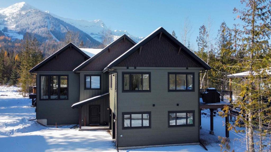 a house in the snow with mountains in the background at Powder House Chalet by Fernie Central Reservations in Fernie