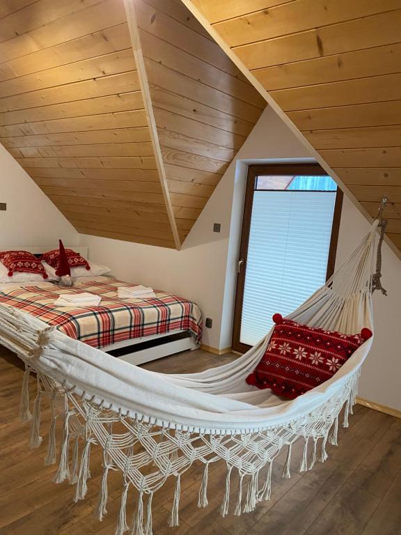 a hammock in a room with a bed and a window at Domek JAWOR in Zakopane