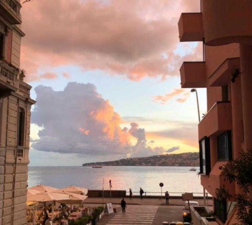 einen Sonnenuntergang über dem Wasser mit Leuten auf dem Bürgersteig in der Unterkunft Naples Luxury Suites B&B in Neapel