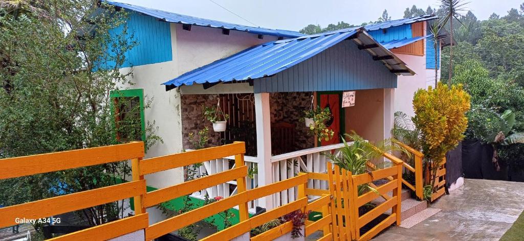una casa con una valla y un techo azul en Cabaña Vistas del Bosque piscina privada en Jarabacoa
