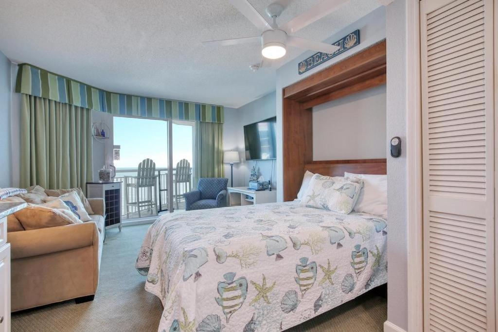 a bedroom with a bed and a chair and a balcony at 2501 S Ocean Blvd, 1127 - Ocean View Sleeps 6 in Myrtle Beach