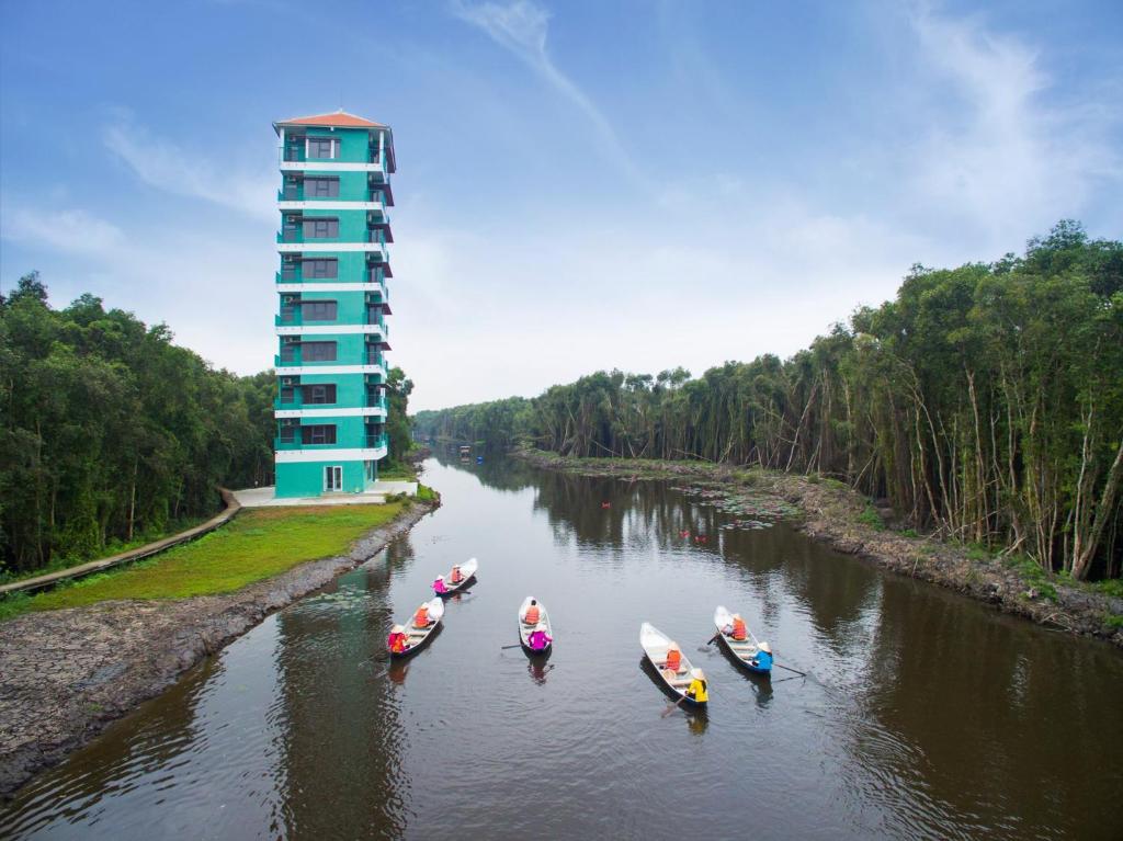 un grupo de barcos en un río con un edificio en KDL Làng Nổi Tân Lập - Tan Lap Floating Village, en Mộc Hóa