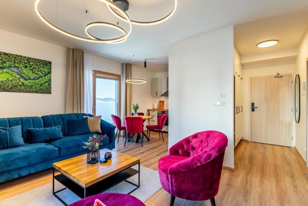 een woonkamer met een blauwe bank en roze stoelen bij Apartmán na Kubínskej holi X33 in Dolný Kubín