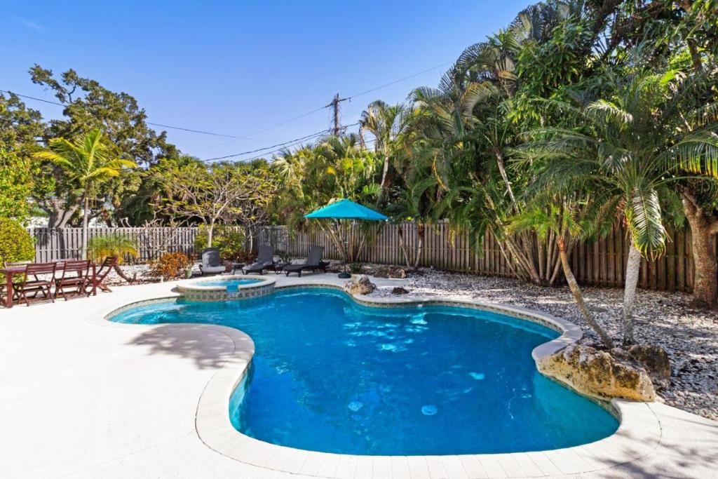 a swimming pool in a yard with a fence and trees at Mangoes on Magnolia in Anna Maria