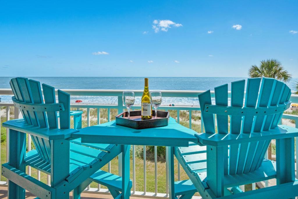 Dos sillas azules y una mesa con una botella de vino en 2501 S Ocean Blvd, 0211 - Ocean Front Sleeps 8 en Myrtle Beach