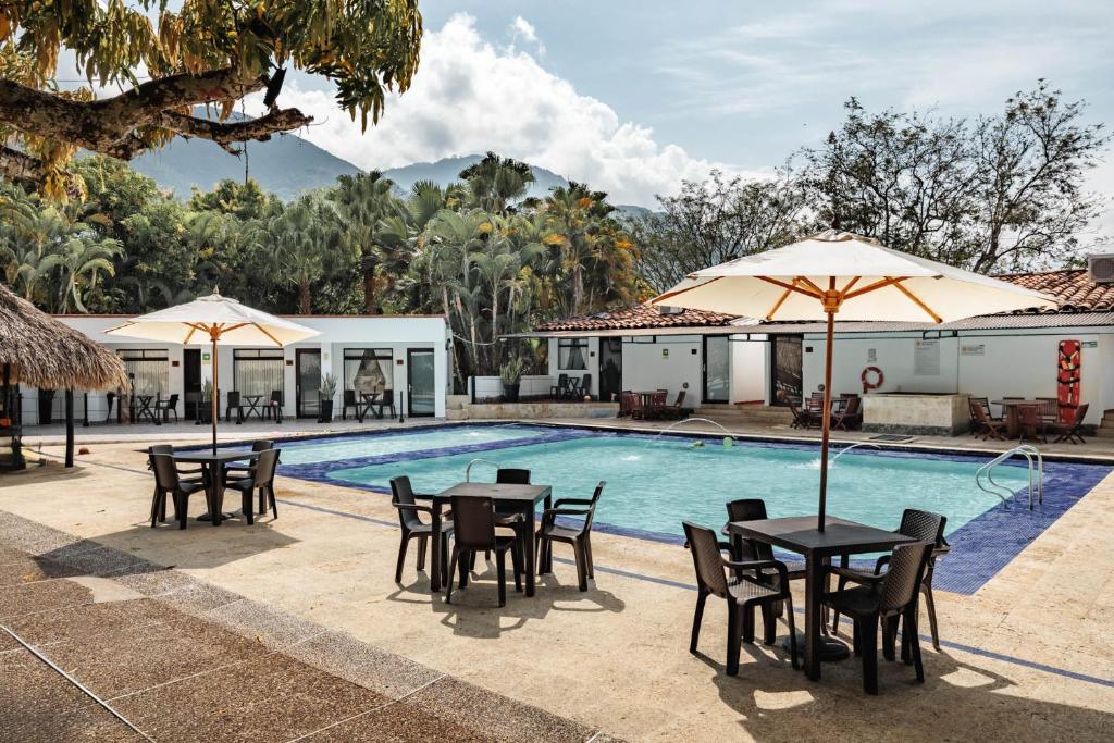 a pool with tables and chairs and umbrellas at Hotel Quimbaya in San Jerónimo