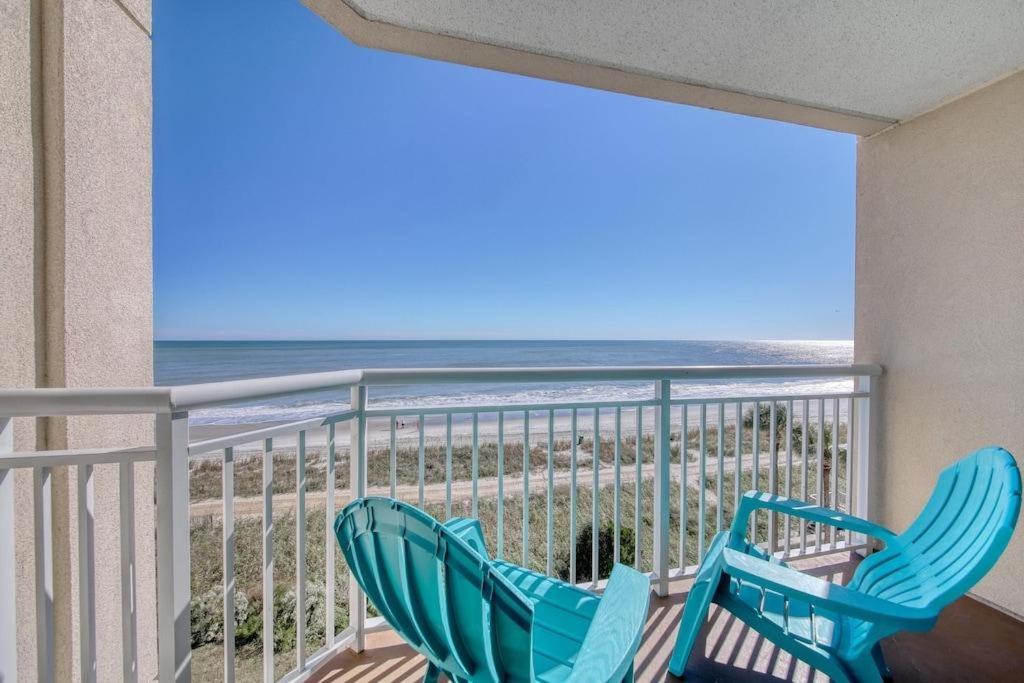 zwei blaue Stühle auf einem Balkon mit Strand in der Unterkunft 2501 S Ocean Blvd, 0407 - Ocean Front Sleeps 6 in Myrtle Beach