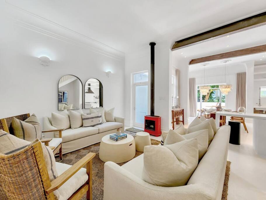 a living room with white furniture and a fireplace at Tranquil Family Home in Green Point in Cape Town