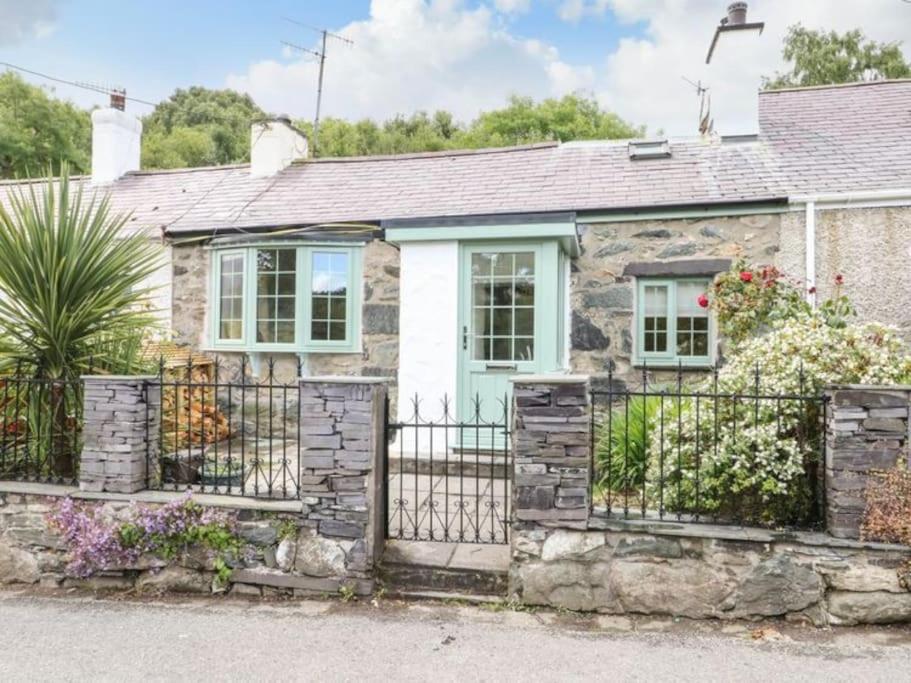 a stone cottage with a gate and fence at Country Cottage with Hot-Tub and Cosy Log Burner in Tregarth