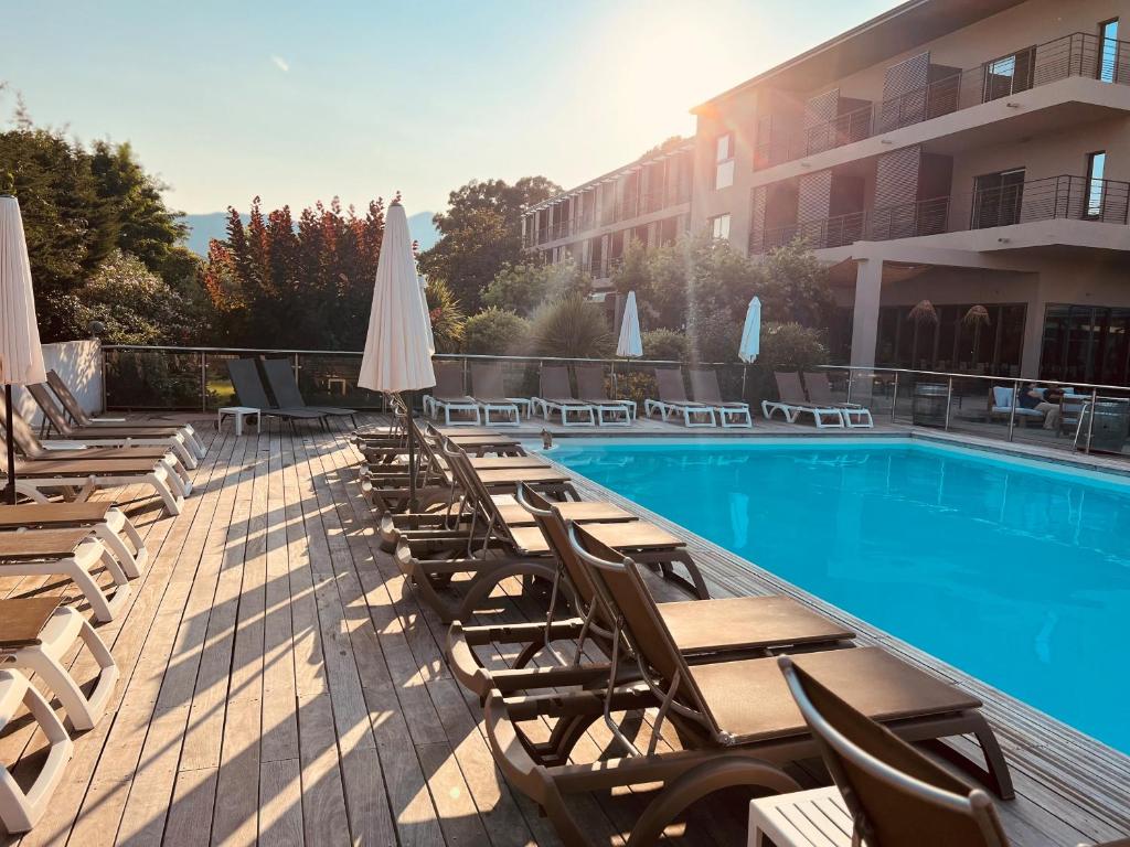 Hôtel Spa Restaurant La Madrague في لوسيانا: مسبح وكراسي ومظلات بجانب مبنى