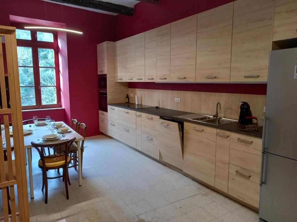 a kitchen with wooden cabinets and a table and a refrigerator at L&#39;Armandière, maison de caractère où règne calme et sérénité. in Pézenes-les-Mines