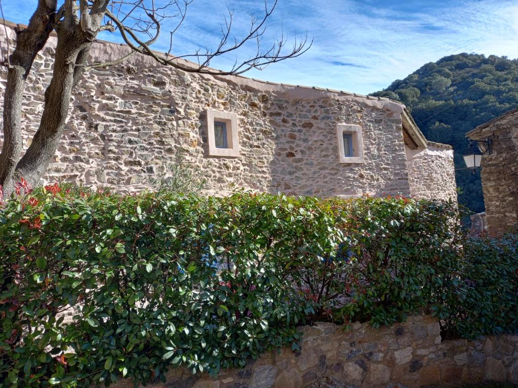 a stone building with bushes in front of it at L&#39;Armandière, maison de caractère où règne calme et sérénité. in Pézenes-les-Mines