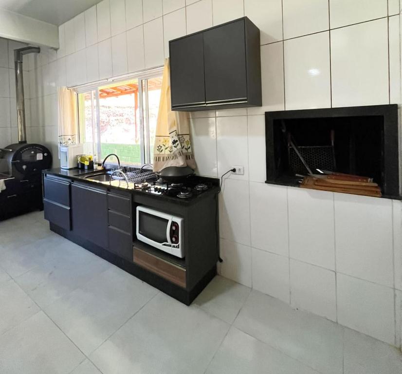a kitchen with a stove and a microwave at Casa de Campo Sol & Luz in Campina Grande do Sul