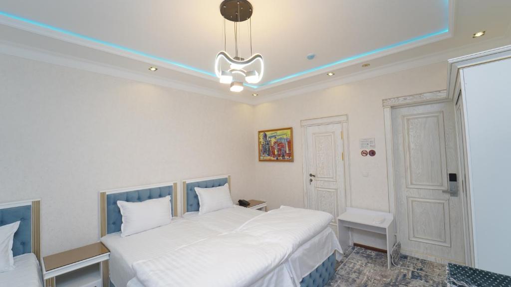 a bedroom with two white beds and a chandelier at Gulnora HOTEL in Uzbankinty
