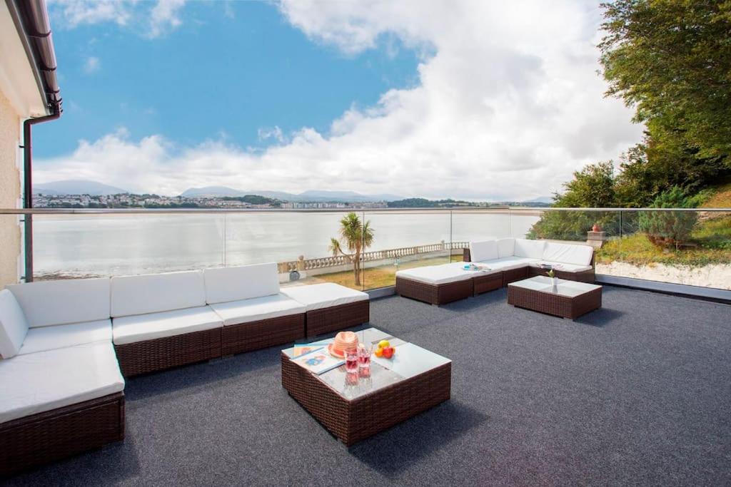 a patio with couches and a view of the water at Sea Front Spacious Apartment on Anglesey in Brynsiencyn