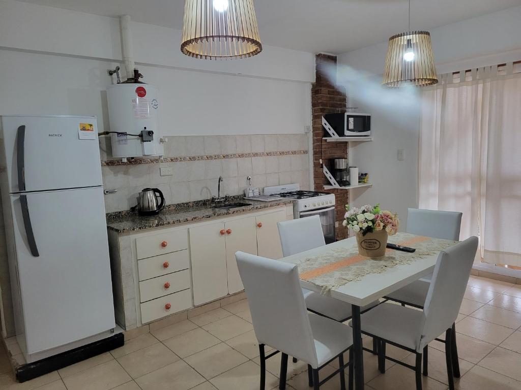 eine Küche mit einem Tisch und einem weißen Kühlschrank in der Unterkunft Departamentos Don Guillo in Alta Gracia