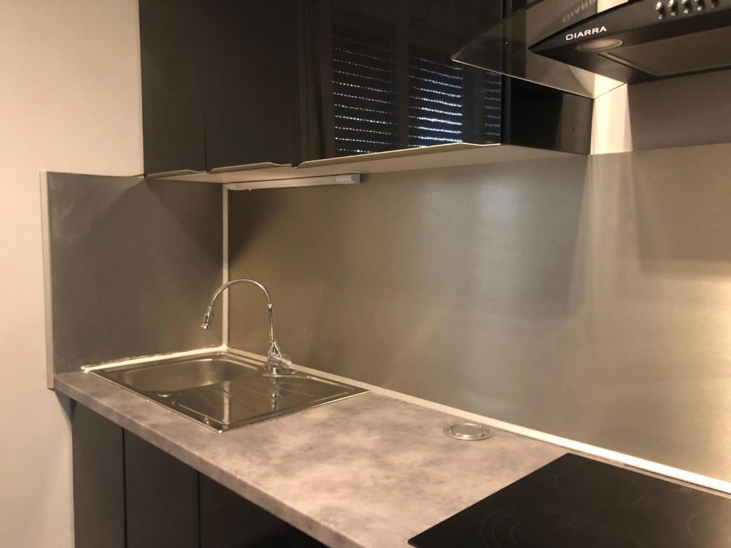 a stainless steel kitchen with a sink and a microwave at Beauvais chambre 1 in Beauvais
