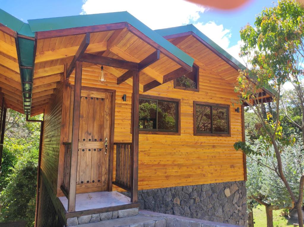 ein winziges Haus mit einer Holztür und einem Dach in der Unterkunft Cabinas El Quetzal in San Gerardo de Dota