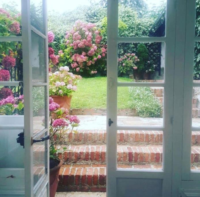 an open door looking out at a garden with flowers at Mima's House · La Casa de Mima in Comillas