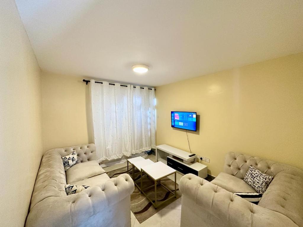 a living room with two couches and a tv at Candy's Staycation in Thika