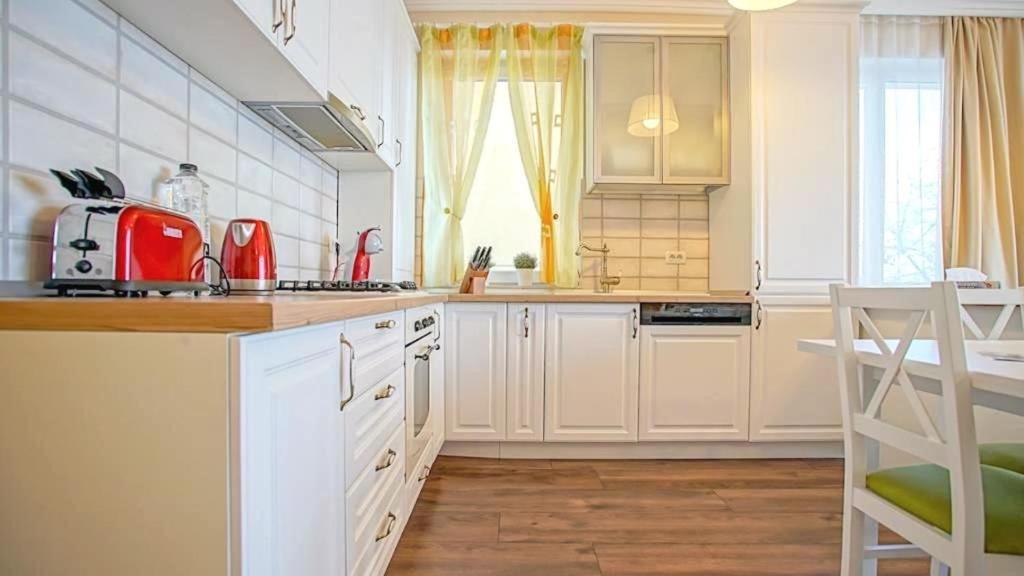 una cucina con armadi bianchi e un apparecchio rosso di Central Maximus Apartment a Braşov