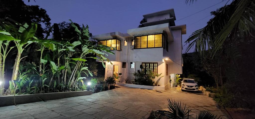 a large white house with lights in the night at Wild Orchid 5BHK Villa & Eco Cottages in Sancoale Valley in Sancoale
