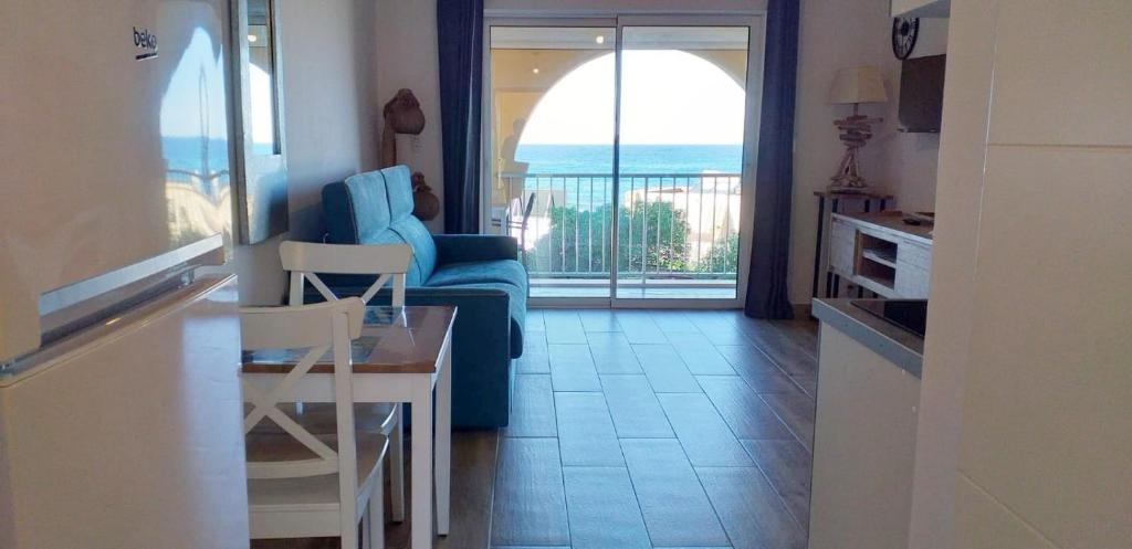 sala de estar con sofá azul y mesa en Studio standing classé avec terrasse vue mer " les pieds dans l'eau " à Algajola en Algajola