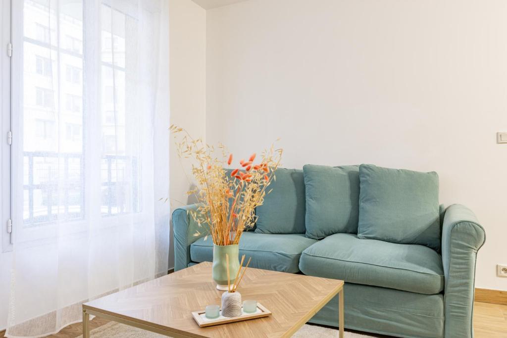 un salon avec un canapé bleu et une table dans l'établissement L'Emeraude by Plaza - Proche Disneyland Paris, à Chessy