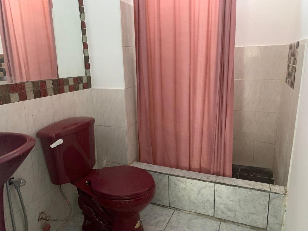 baño con aseo rojo y cortina de ducha rosa en MiniDepar en Salinas
