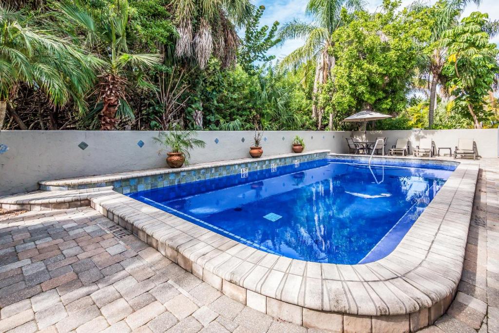 a swimming pool in a backyard with chairs and trees at Seabreeze D in Holmes Beach