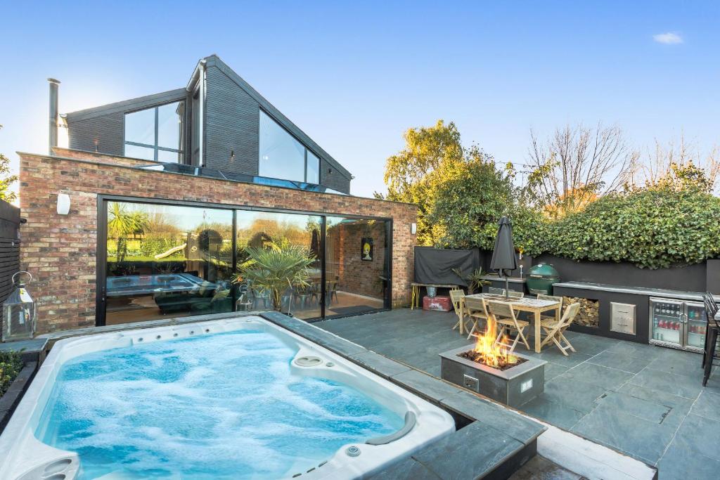 une arrière-cour avec une piscine et une maison dans l'établissement Nutkin Barn - Contemporary home in West Sussex, à Chichester