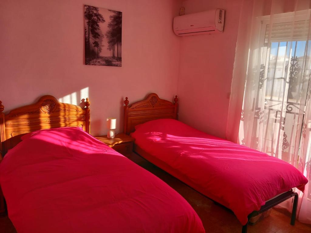 2 camas en una habitación con sábanas rojas y una ventana en A room with a Sun view B&B, en Orihuela