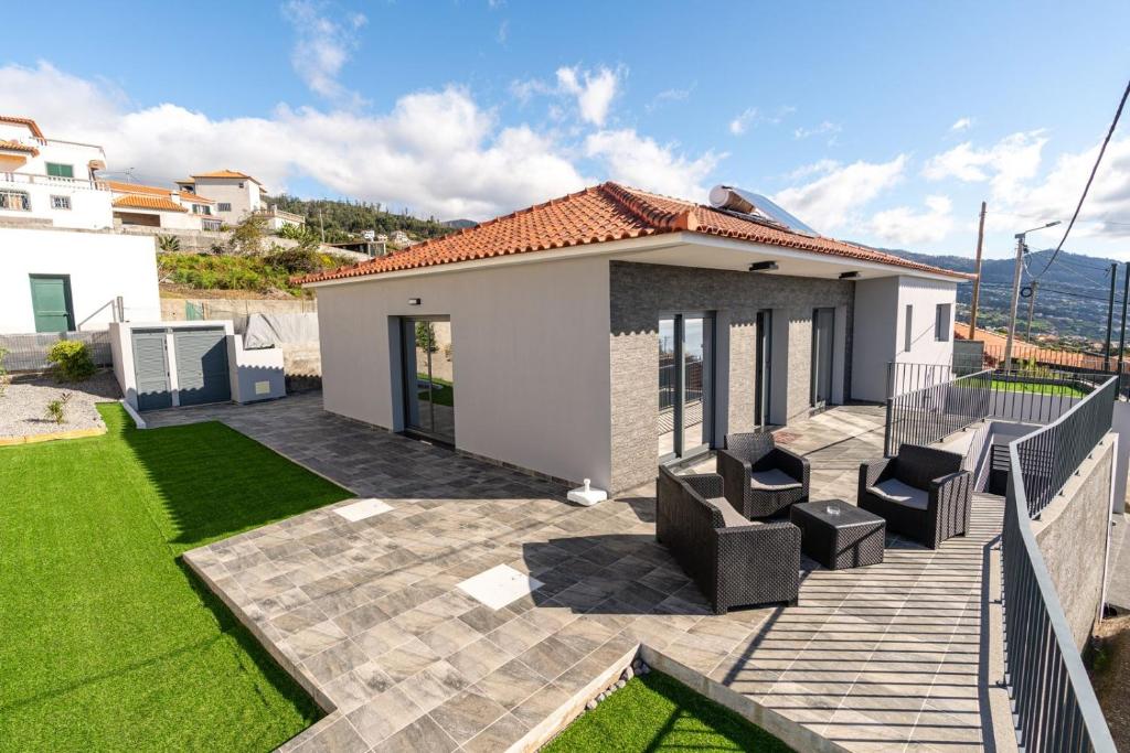 un patio trasero con un patio con sillas y césped en Casa Barros Serra en Calheta