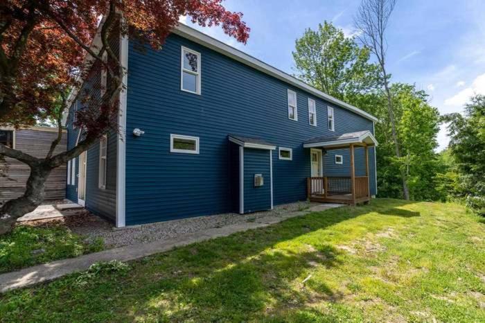 een blauw huis met een veranda en een tuin bij The Cottages at Harvey Lake in Northwood