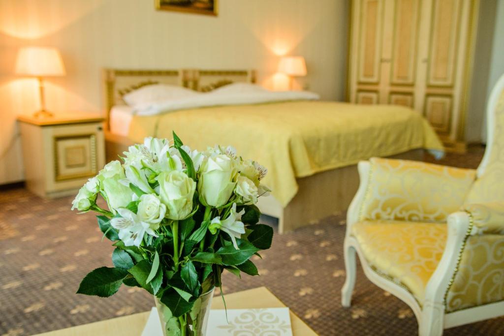 eine Vase mit weißen Blumen auf einem Tisch in einem Hotelzimmer in der Unterkunft SK Royal Hotel Moscow in Moskau