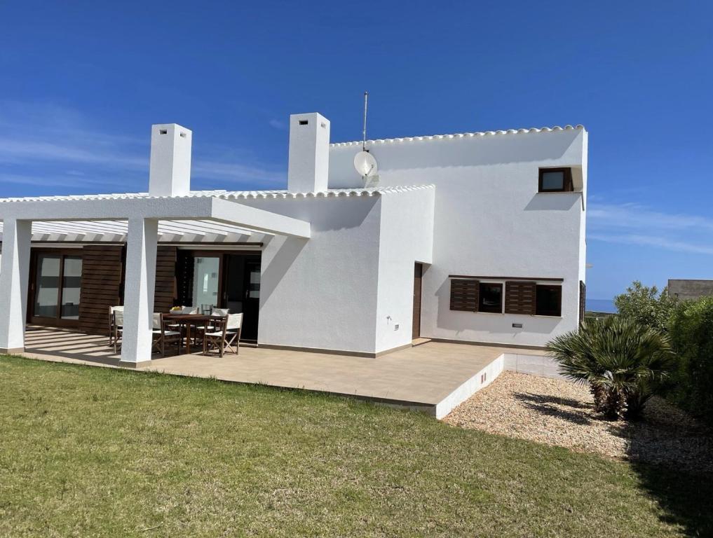 een wit huis met een terras en een tafel bij Villa d'Es Bot in Cala Morell