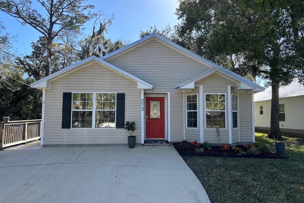 una pequeña casa blanca con una puerta roja en The Golden Hideaway en St. Augustine