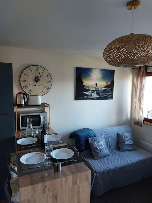 un salon avec un canapé et une horloge au mur dans l'établissement Appartement Saint Gervais proche centre, à Saint-Gervais-les-Bains