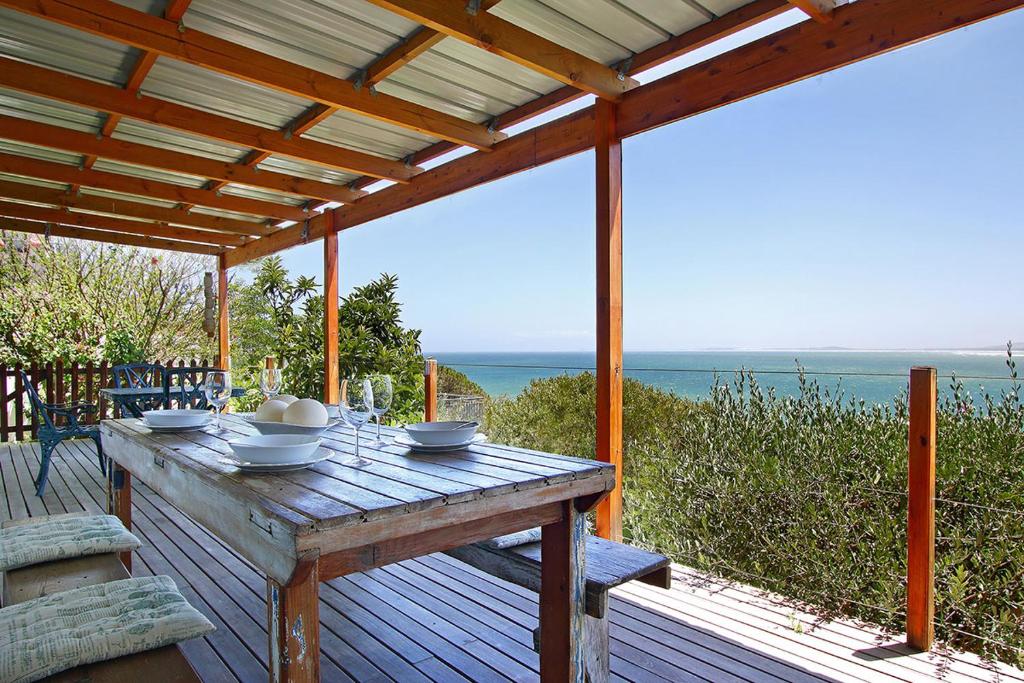 einen Holztisch auf einer Terrasse mit Meerblick in der Unterkunft Suikerbossie 82 by HostAgents in Gordonʼs Bay