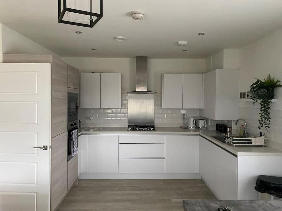 cocina blanca con armarios blancos y fogones en Beautiful Modern Tranquil Two Bedroom Apartment, en Swanscombe