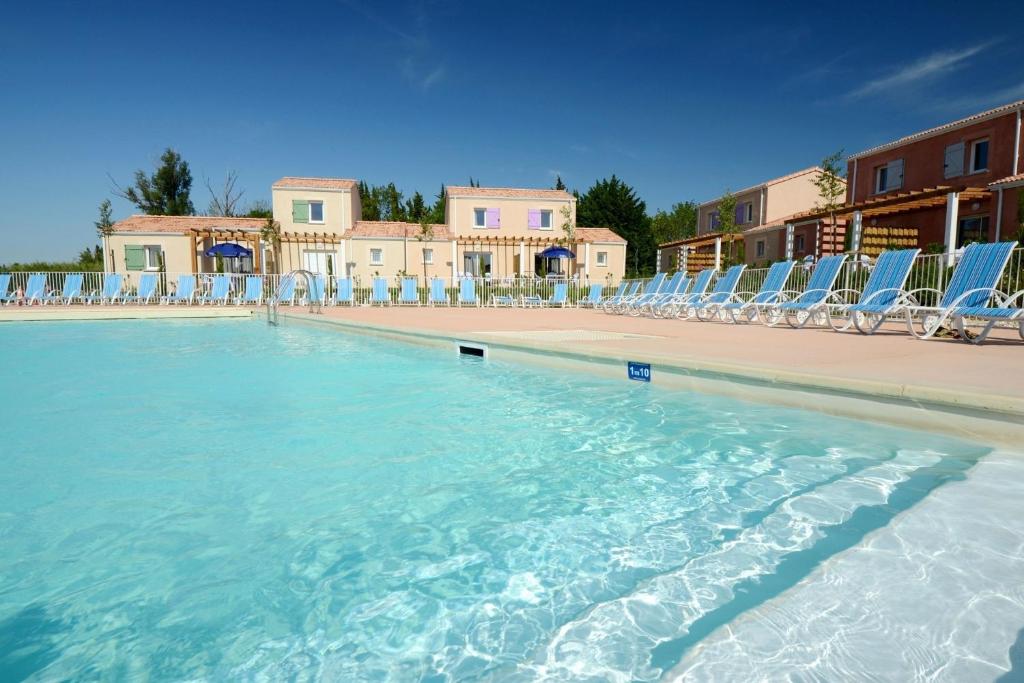 a swimming pool with chairs and a swimming pool at Résidence Odalys Le Mas des Alpilles in Paradou