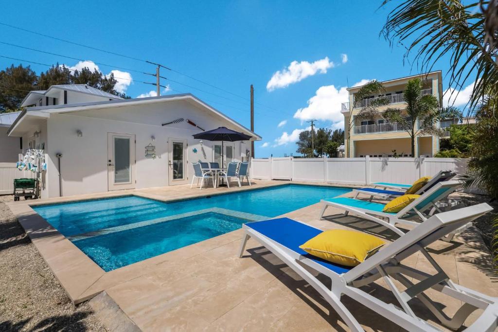 a swimming pool with two lounge chairs and a house at Seagrape Cottage in Bradenton Beach